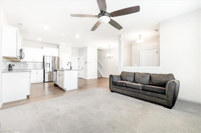 living area with stairs, recessed lighting, baseboards, and light colored carpet