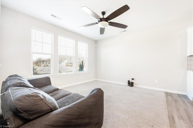 living room with visible vents, baseboards, and ceiling fan