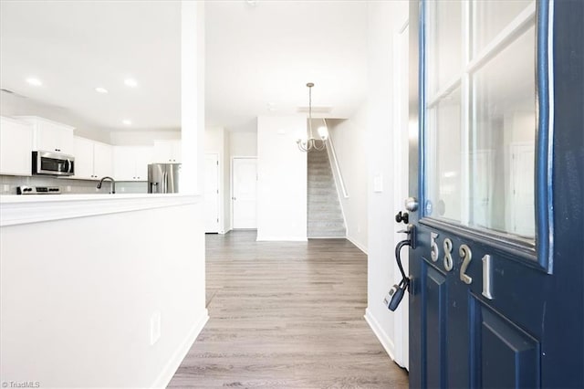 entryway featuring light wood finished floors, baseboards, stairway, and recessed lighting