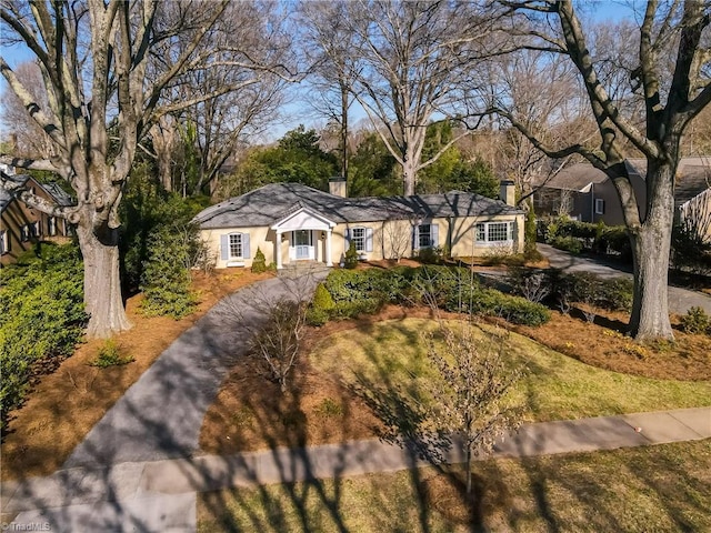 single story home with a chimney and stucco siding