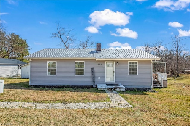 view of front of property with a front yard, metal roof, and a chimney