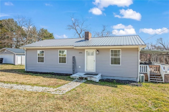 view of front of house featuring a chimney, metal roof, and a front yard