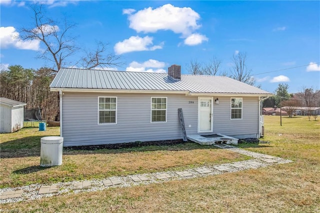 view of front of home featuring a chimney, metal roof, and a front yard