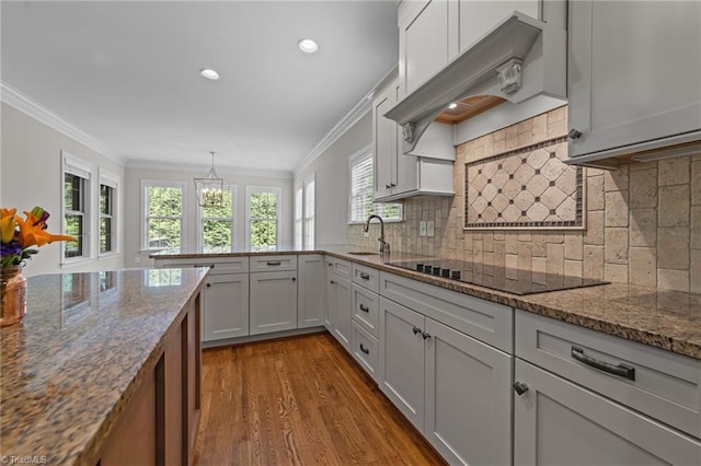 2507 Duck Club Rd, Greensboro, NC 27410 - kitchen with black electric stovetop, exhaust hood, dark wood finished floors, a chandelier, and dark stone countertops