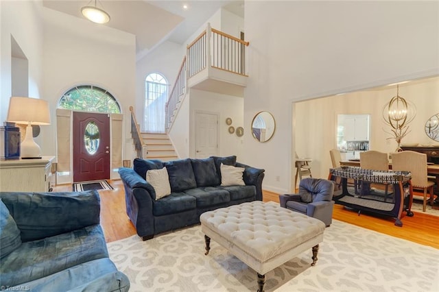 living room featuring light wood-type flooring, a high ceiling, and a notable chandelier