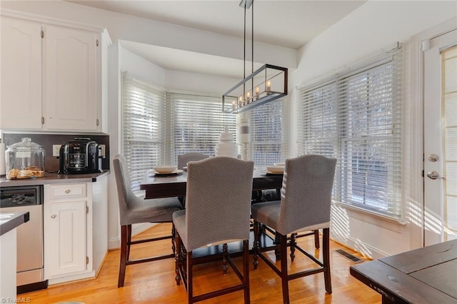 dining area with plenty of natural light, light wood-type flooring, and an inviting chandelier