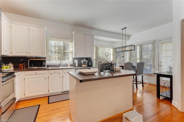 kitchen with white cabinetry, hanging light fixtures, appliances with stainless steel finishes, and a kitchen island