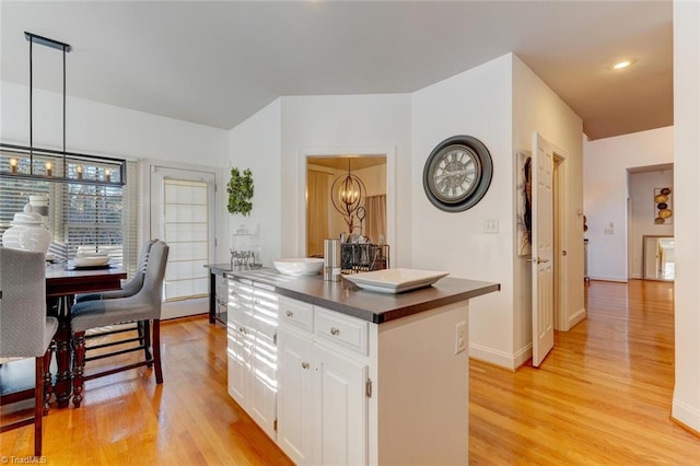 kitchen featuring white cabinets, a center island, light hardwood / wood-style flooring, and hanging light fixtures