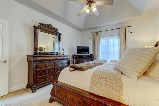 carpeted bedroom with ceiling fan and a tray ceiling