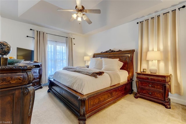 carpeted bedroom featuring ceiling fan and a raised ceiling