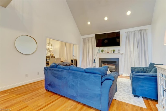 living room with high vaulted ceiling, wood-type flooring, and a notable chandelier