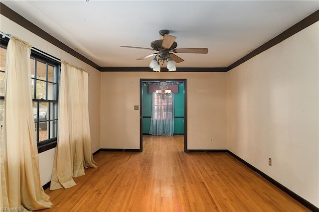 empty room with ceiling fan with notable chandelier, ornamental molding, and light hardwood / wood-style flooring