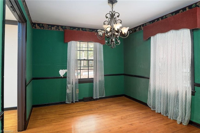 spare room featuring a chandelier and wood-type flooring