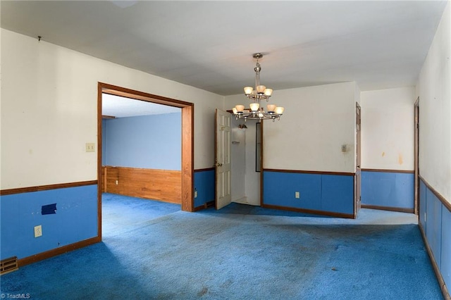 spare room featuring carpet and an inviting chandelier