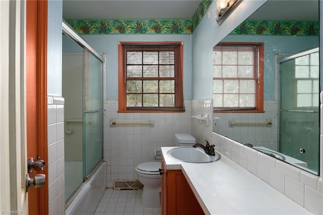 full bathroom with toilet, tile patterned floors, tile walls, and a healthy amount of sunlight