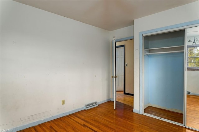 unfurnished bedroom featuring a closet and hardwood / wood-style flooring