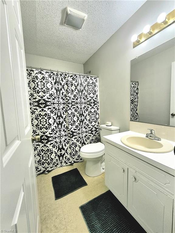 1018 Cedar Place Ct, Winston-Salem, NC 27107 - full bathroom featuring vanity, toilet, a textured ceiling, and tile patterned floors