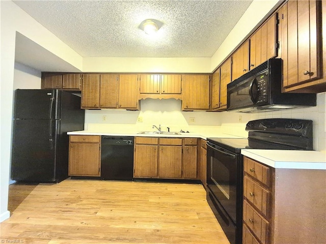 1018 Cedar Place Ct, Winston-Salem, NC 27107 - kitchen featuring black appliances, a textured ceiling, a sink, light wood-type flooring, and brown cabinetry