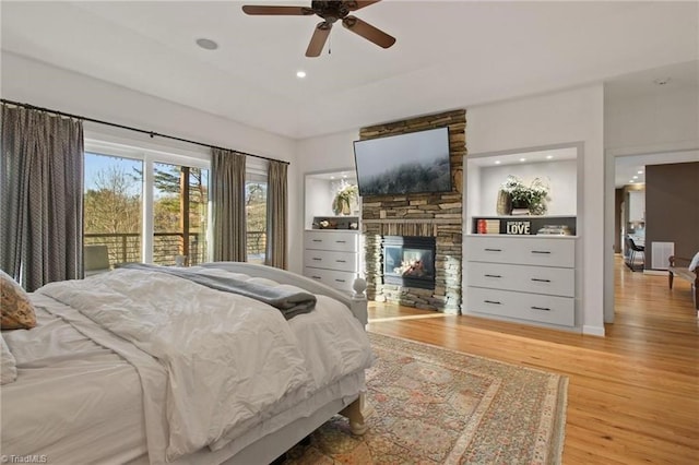 bedroom with ceiling fan, access to exterior, light hardwood / wood-style flooring, and a fireplace