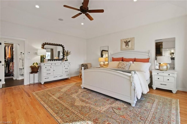 bedroom with ceiling fan, a walk in closet, a closet, and hardwood / wood-style flooring