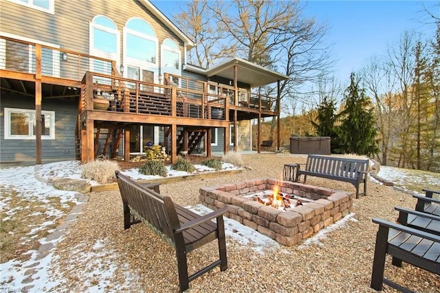 exterior space with a wooden deck, a hot tub, and a fire pit