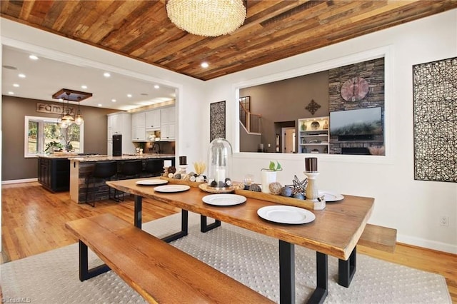 dining area with light wood-type flooring, wood ceiling, and an inviting chandelier