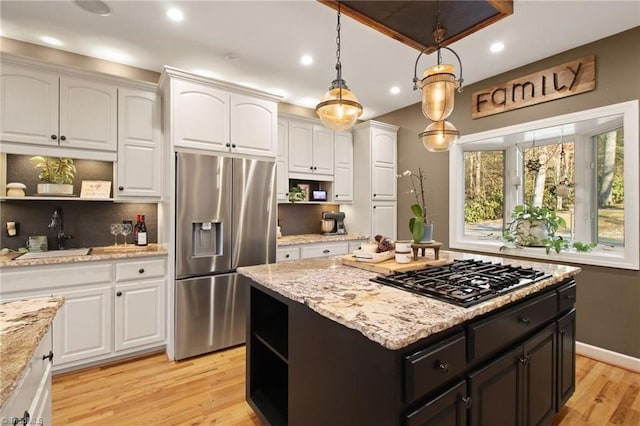 kitchen with black gas cooktop, stainless steel fridge, sink, and white cabinetry