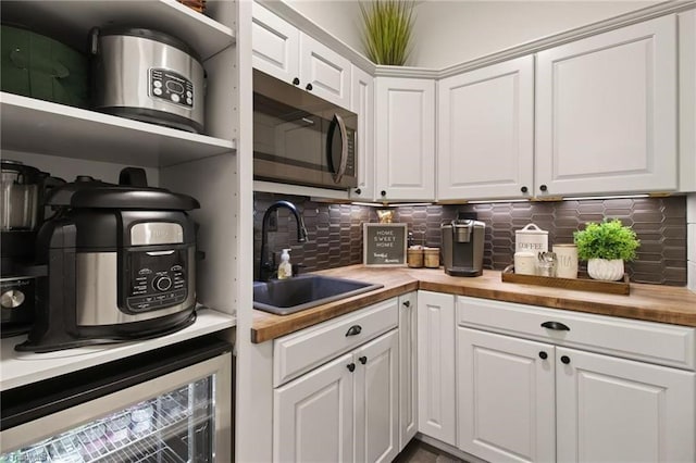 kitchen with white cabinetry, butcher block counters, decorative backsplash, wine cooler, and sink