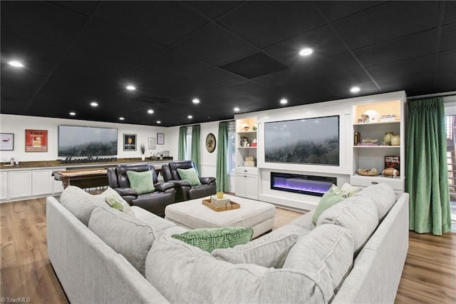 home theater with light wood-type flooring, a paneled ceiling, and built in features