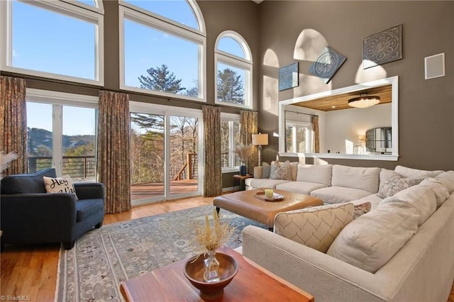 living room with a towering ceiling, a wealth of natural light, and light hardwood / wood-style floors