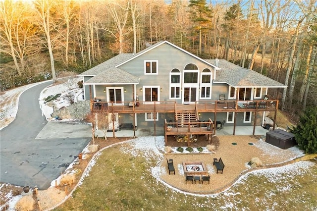 back of house with an outdoor fire pit, a hot tub, a deck, and a patio