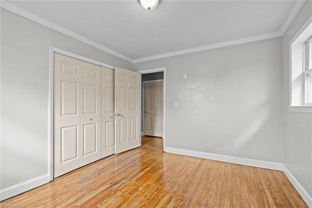 unfurnished bedroom featuring ornamental molding, a closet, and light wood-type flooring