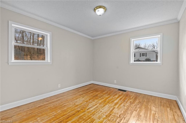 spare room with ornamental molding, a textured ceiling, and light hardwood / wood-style floors