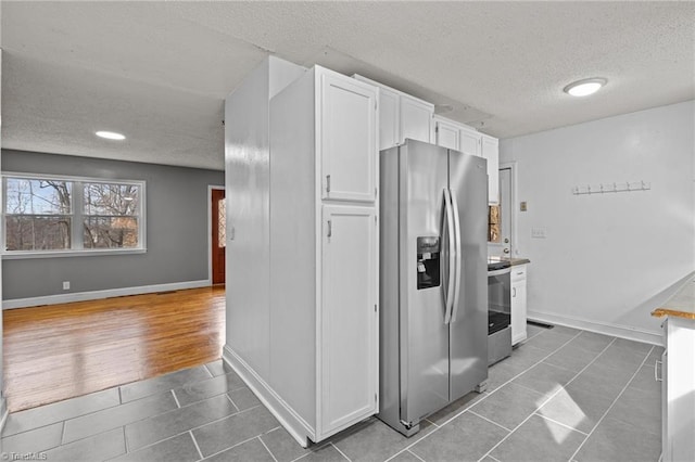 kitchen with white cabinetry, a textured ceiling, dark tile patterned floors, and appliances with stainless steel finishes