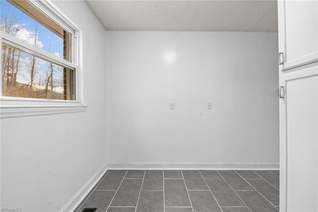 tiled spare room featuring a textured ceiling