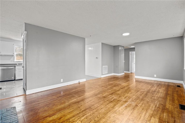 unfurnished living room with a textured ceiling and light wood-type flooring