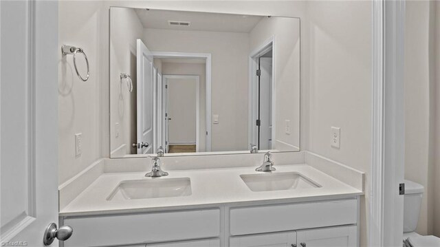 3765 Baden Rd, Winston-Salem, NC 27107 - bathroom featuring double vanity, toilet, visible vents, and a sink