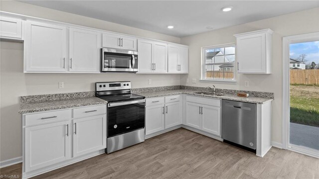 3765 Baden Rd, Winston-Salem, NC 27107 - kitchen featuring light stone countertops, a sink, light wood finished floors, stainless steel appliances, and white cabinetry
