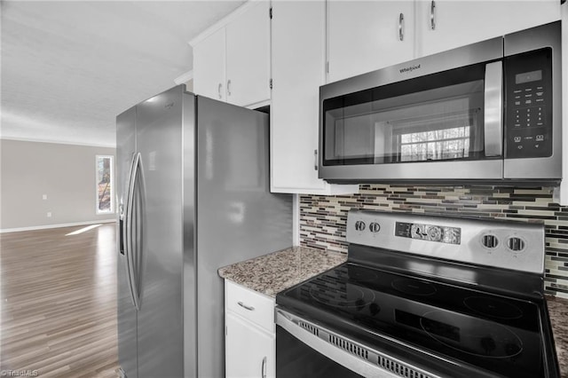 kitchen with wood finished floors, baseboards, white cabinets, appliances with stainless steel finishes, and decorative backsplash