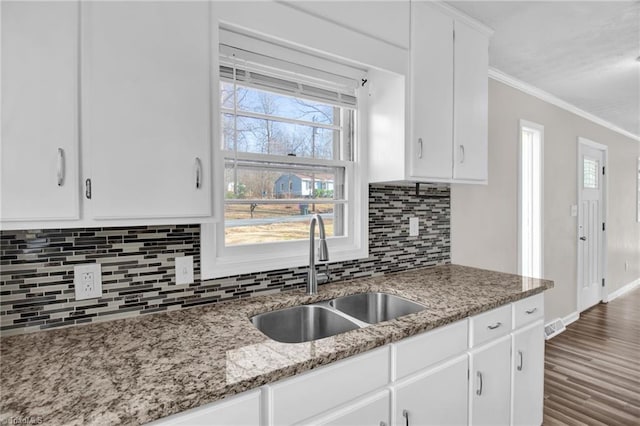 kitchen with crown molding, white cabinetry, a sink, and wood finished floors