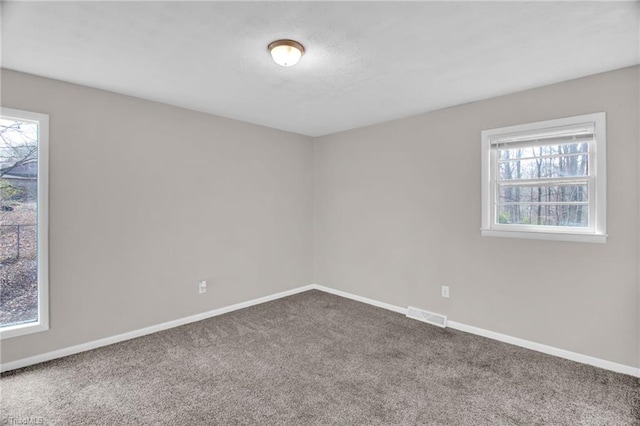 carpeted empty room featuring a textured ceiling, visible vents, and baseboards