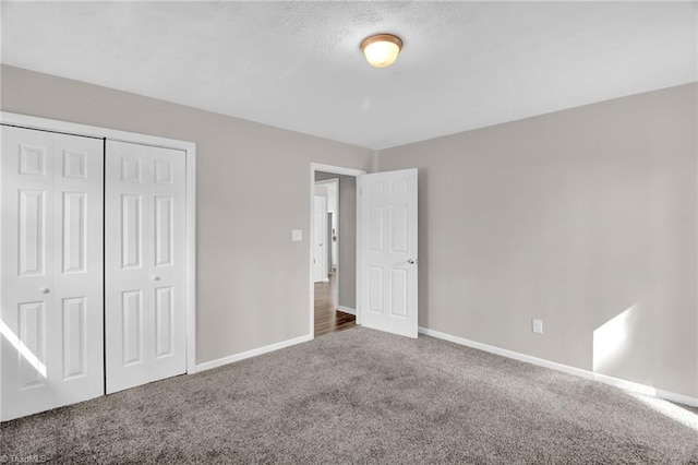 unfurnished bedroom featuring carpet floors, baseboards, and a closet