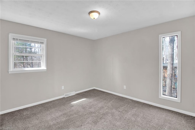 empty room featuring carpet, visible vents, and baseboards