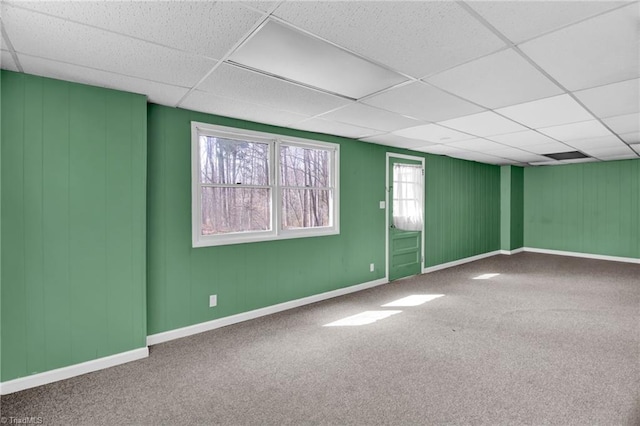 carpeted spare room featuring baseboards and a drop ceiling