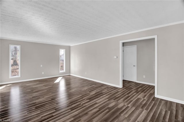 empty room featuring ornamental molding, dark wood finished floors, and baseboards