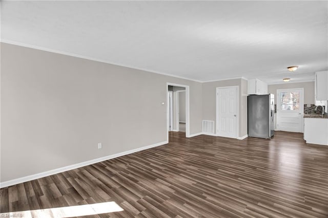 unfurnished living room featuring baseboards, dark wood finished floors, visible vents, and crown molding