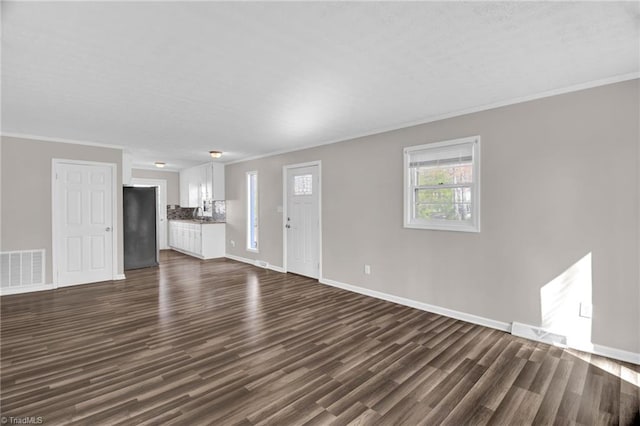 unfurnished living room with dark wood-style floors, visible vents, and crown molding