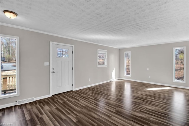 foyer entrance with a textured ceiling, ornamental molding, dark wood finished floors, and visible vents