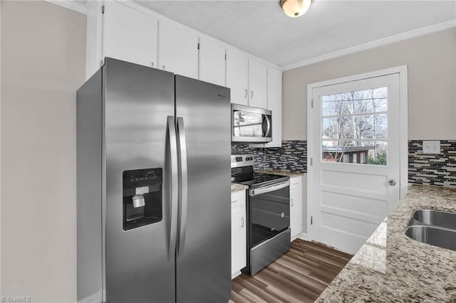 kitchen with tasteful backsplash, white cabinets, dark wood finished floors, appliances with stainless steel finishes, and crown molding