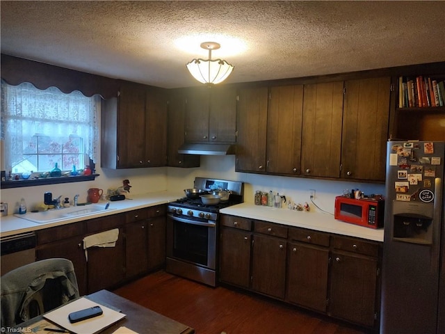 kitchen with sink, dark wood-type flooring, stainless steel appliances, a textured ceiling, and dark brown cabinets